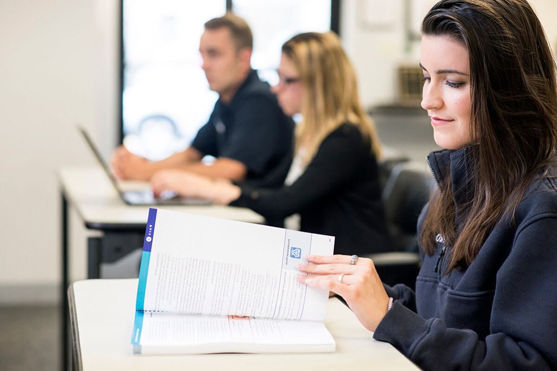 students using course catalog search Young woman browsing a textbook in a classroom