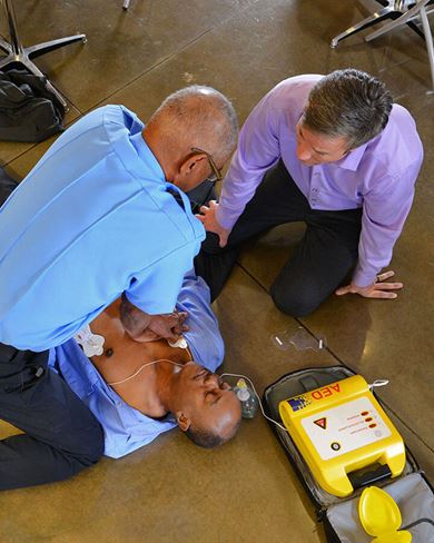 male paramedic and male office personnel using an AED male paramedic and male office personnel using an AED image